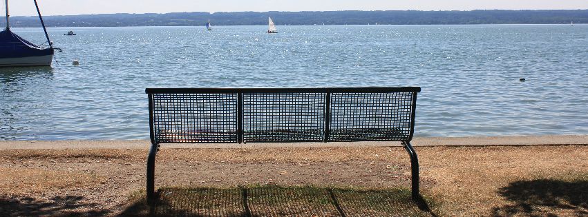 Bank am See, im Hintergrund Segelboote