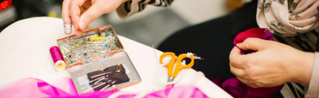 Hände, die aus einer Dose Stecknadeln rausnimmt