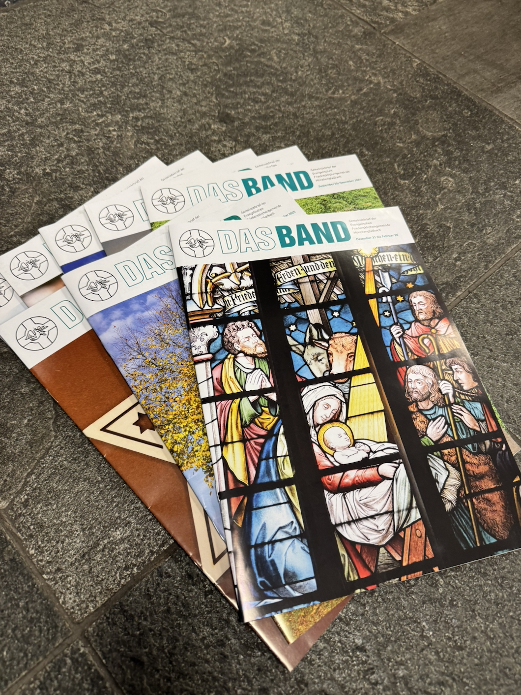 Bild von unterschiedlichen Ausgaben des Gemeindebriefes "Das BAND"